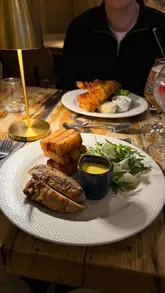 A montage video showcasing the interior, exterior, food, and drinks at The Stables restaurant located within Beamish Hall. The video features close-ups of plated dishes like chicken bearnaise and fish and chips, as well as dessert and drink shots, set to music with text overlays providing context.