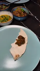 A vlog-style review of a £10 lunch deal at a restaurant called Pach Bhai, featuring a variety of traditional dishes like beef bhuna, daal, and chicken liver.