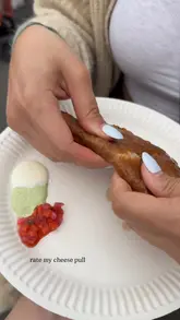 A short, focused clip featuring a close-up of a gluten-free cheese and leek empanada being pulled apart to reveal the melted cheese filling, filmed at a food festival.