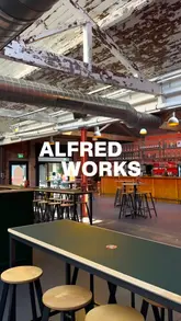 A fast-paced montage showcasing Alfred Works, a food hall in Digbeth, Birmingham. The video highlights the interior space, including arcade games, and features various food offerings from different stalls, including tacos, chicken, and nachos.
