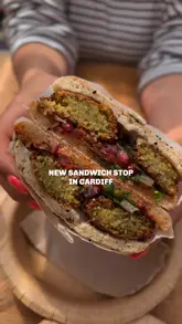 A short, casual vlog-style video showcasing a new sandwich shop in Cardiff called Lahmacun, featuring falafel sandwiches, beer, and cookies in an outdoor seating area.
