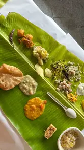 The video features a couple visiting Tamila in Soho to try their new South Indian banana leaf thali menu. It starts with a personal anecdote about a wedding, then transitions to the restaurant, showing the interior, the variety of dishes in the thali, and the creators enjoying the food.