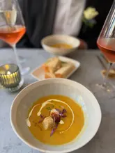 A high-quality, well-composed shot of a soup course served during a wedding breakfast. The focus is sharp on the garnish, with a shallow depth of field that creates a warm, celebratory atmosphere.