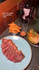 A fast-paced, music-synced montage showcasing a variety of dishes and cocktails at a restaurant, including steak, tacos, and smoked meats. The video focuses on close-up shots of the food being served and eaten, highlighting the textures and presentation.