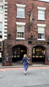 Here are a few options for your SEO alt text, depending on the focus of the image:

**Option 1 (Focus on the pub exterior/beer garden):**
Couple enjoying a spring staycation in the beer garden of The Pied Bull, Chester’s oldest historic coaching inn.

**Option 2 (Focus on the building/brand):**
Historic exterior of The Pied Bull pub, hotel, and microbrewery in Chester city centre.

**Option 3 (More descriptive/vibe-focused):**
Cosy atmosphere at The Pied Bull, a historic 12th-century coaching inn and microbrewery in Chester.

**SEO Tip:** I recommend **Option 1** as it captures both the location and the "staycation" vibe which is great for travel search intent.