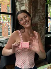A bright, engaging photo of a participant at a cookie decorating workshop, holding up their creation. The natural lighting and relaxed, happy expression of the creator make the activity look inviting and fun.