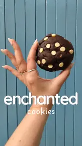 A review and taste test of 'Enchanted Cookies,' a local delivery service in Brighton & Hove. The creator showcases various cookie flavors, including OG Chocolate Chip, Dubai Chocolate, and Biscoff, demonstrating their texture by breaking them open and pairing them with ice cream.