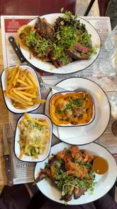 A review-style reel featuring a visit to Chop Shop Bar & Grill, showcasing a variety of meat-heavy dishes including tacos, a butcher's block platter, chicken, and mac and cheese.
