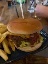 A close-up, eye-level shot of a standard burger and fries served on a dark blue plate, captured during a bottomless brunch.