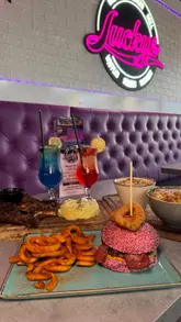 A short, music-led montage showcasing the interior and food offerings at Luckys Diner. The video features quick cuts between neon decor, plated dishes like lamb chops and a pink-bun burger, and various desserts and mocktails.