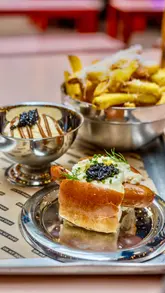 The creator reviews a new 'bougie' caviar-topped hotdog and sundae special from Oh My Dog, available at Seven Dials Market and Lord Napier Star. The video features close-ups of the food preparation, the creator's reaction, and a unique 'hack' involving dipping truffle fries into the sundae.