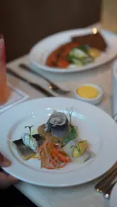 A high-quality promotional video for Brasserie Angelica and Gambit Bar at The Newman hotel, featuring a montage of the elegant interior, plated dishes like salmon and steak, craft cocktails, and the venue's atmosphere.