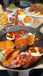 A first-person review of a brunch cafe called Dobar, featuring a variety of dishes including pancakes with fried chicken, a full English breakfast, French toast, poached eggs with Greek yogurt, and banana pudding. The creator provides commentary on the food quality and presentation.