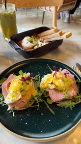 A short, aesthetic reel showcasing the interior and brunch menu of Double Eleven Cafe in Leeds. The video features close-ups of dishes like Eggs Benedict and Shakshuka, various hot and iced drinks, and a display of baked goods, set to music with text overlays detailing the venue and a special brunch offer.