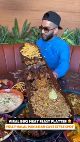 A creator reviews a Pan Asian restaurant, highlighting a large BBQ meat feast platter. The video features the creator eating various items from the platter, including chicken, lamb, noodles, and bao buns, while providing commentary on the food quality and value.