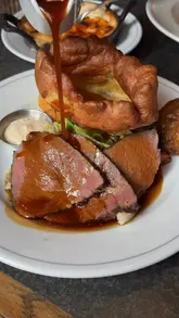 A high-quality montage showcasing a Sunday roast experience at The Trafalgar Chelsea, featuring close-ups of roast beef, sides, and dessert, set to music.