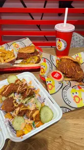 A fast-paced food review video showcasing various menu items from Dave's Hot Chicken, including sliders, loaded fries, mac and cheese, and milkshakes, filmed with close-up shots to emphasize texture and sauce.