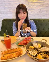 A photo of a creator at an Italian restaurant in Chelsea, featuring a spread of oysters, focaccia, and cocktails, promoting a fixed-price menu concept.