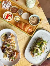 A high-angle flat lay shot of a brunch spread featuring a kids' sharing board, French toast, and drinks on a wooden table.