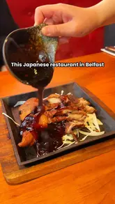 Here are a few options for your SEO alt text (all under 125 characters):

**Option 1 (Descriptive & SEO-focused):**
A colorful spread of Japanese sushi, katsu curry, pork dumplings, and cocktails at Osaka restaurant in Belfast.

**Option 2 (Action-oriented):**
Diners sharing a variety of Japanese dishes including sushi and katsu curry at Osaka restaurant on Boucher Road, Belfast.

**Option 3 (Concise):**
Japanese food platter with sushi, katsu curry, and dumplings at Osaka restaurant, Belfast.