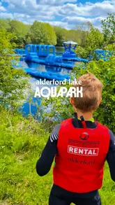 A promotional video for the Alderford Lake Aquapark, featuring footage of people navigating a large inflatable obstacle course on a lake. The video uses fast-paced editing and text overlays to highlight the experience, safety requirements, and suitability for groups and families.