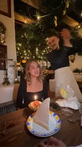The video captures a birthday celebration at an Italian restaurant, featuring a waiter singing and presenting a large lemon meringue pie to the birthday girl. The setting is warm and atmospheric, with the video focusing on the celebratory moment and the dessert.