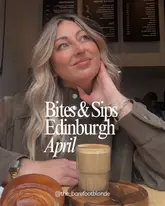 A lifestyle-focused cover image for an Edinburgh food guide, featuring a woman in a cafe setting with a coffee and pastry in the foreground. The image uses a shallow depth of field to focus on the subject while providing context for the venue.