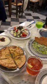 A review of Taverna Ermou in London, showcasing a variety of Greek dishes including spinach and feta dip, Greek salad, grilled octopus, kebabs, and a phyllo-based dessert. The video uses a handheld vlog style to present the food and the restaurant's atmosphere.