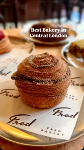A creator visits Fred Bakery in Oxford Circus, showcasing the wide variety of pastries, coffee, and savoury items available. The video features close-up shots of the food, the interior of the bakery, and the creator enjoying the items, highlighting the quality and appeal of the products.