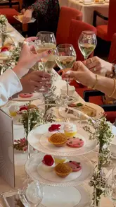 A high-quality, polished reel showcasing the 'Peninsula in Bloom' afternoon tea service at The Peninsula London. The video features elegant shots of the dining room, a live piano player, close-ups of the tea service, pastries, and champagne, as well as a glimpse of a dog in the hotel.