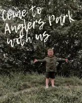 A candid, eye-level shot of a young child standing in a park, used to promote a family-friendly outdoor trail and play area.