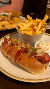 A vlog-style reel showcasing a dining experience at The Pied Bull in Chester. The video features a variety of pub classics, including meatballs, fried cheese, a hotdog, and fish and chips, while highlighting the cozy, historic interior of the venue.