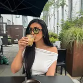 A portrait shot of a woman enjoying a coffee at an outdoor cafe setting, likely during a brunch visit.