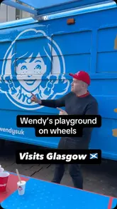 The video features a creator visiting the Wendy's Frosty Funhouse pop-up bus in Glasgow. It highlights various interactive activities available inside, including a braid bar, a photo booth, a ball pit, and a game of Frosty Pong outside, while also showing the creator enjoying a Frosty.