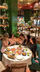 A high-quality montage showcasing the lush, jungle-inspired interior of a high-end London restaurant. The video features close-ups of fire-grilled meats, vibrant salads, theatrical cocktails, and live musical entertainment, creating an inviting and energetic atmosphere for a group dining experience.