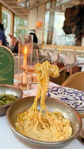 A polished showcase of a high-end London restaurant, featuring elegant interiors, table-side pasta preparation, and a variety of Mediterranean-inspired dishes and drinks.