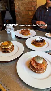A promotional video for Regency House in Belfast, showcasing their expanded pancake menu. The video features close-up shots of four different pancake styles: blueberry, bacon and maple, sausage egg and cheese, and lox (smoked salmon). It includes shots of the food being prepared or served, along with a brief look at the menu and some accompanying drinks.