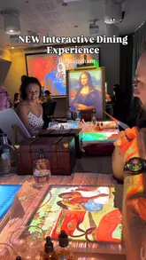 A promotional video for '7 Paintings' in Birmingham, showcasing an immersive dining experience where the table acts as a canvas with projection mapping. The video highlights the interactive nature of the meal, including painting on edible canvases and solving riddles, alongside the seven-course menu inspired by famous artists.