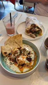 A short, energetic reel featuring a brunch visit to Kofi & Co. in Wetherby. The video highlights the new Spring/Summer menu, showcasing dishes like Turkish eggs with chorizo and a chicken shawarma wrap, alongside drinks like a smoothie and iced latte. The creator is shown enjoying the meal in the cafe setting.