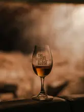 A moody, atmospheric shot of a whisky glass featuring the branding of 'The Lost Close' in Edinburgh. The image uses a shallow depth of field and warm lighting to evoke a sense of history and exclusivity, fitting for an underground whisky tasting venue.