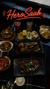 A food review video showcasing a variety of Indian dishes at Hero Saab, including chaat, curries, and mixed grills, presented in a montage format.
