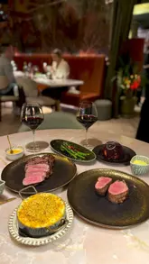 A high-quality montage showcasing a variety of dishes and drinks at Kobe Steakhouse in Mayfair, featuring close-ups of steaks, pasta, sides, and creative desserts.