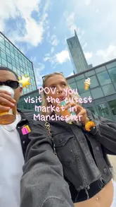 A day-in-the-life style reel documenting a visit to Campfield Market in Manchester. The video follows a couple as they browse various stalls, including a sticker machine, hot sauce tasting, and print shops, while sampling street food, drinks, and ice cream.