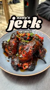 A creator visits Natty's Jerk in Portsmouth, showcasing the beach-themed venue, the charcoal cooking process, and a variety of Caribbean dishes including jerk chicken, mac and cheese, and curry goat.