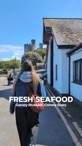 A short, handheld video showcasing a visit to a seafood shop on Conwy Quay. The video features a walk towards the venue, a look at the shop's exterior and counter, and a close-up of a seafood mix being seasoned and sauced.