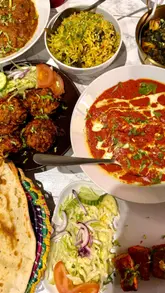 A vlog-style review of Kumars Kitchen in Bedford, featuring a variety of Indian and Pakistani dishes including butter chicken, tandoori salmon, and lamb dansak.