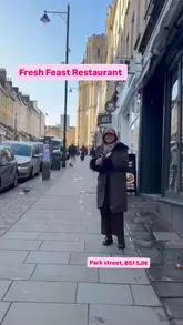 A vlog-style review of Fresh Feast restaurant in Bristol, featuring two creators trying a variety of Chinese dishes including duck pancakes, chow mein, and spring rolls. The video highlights the restaurant's interior, menu options, and the presence of karaoke facilities.