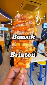 A fast-paced, first-person POV video showcasing the menu and interior of the new Bunsik branch in Brixton, featuring various Korean street food items like corn dogs, fried chicken, rice bowls, and kimbap.