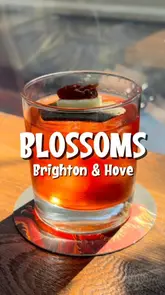 A montage-style reel showcasing a variety of cocktails and Japanese-inspired small plates at Blossoms in Brighton. The video features close-up shots of food preparation, finished dishes, and the venue's interior and outdoor seating area, set to music.