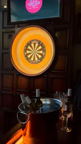 Here are a few options for your alt text, depending on what is actually in the image:

**Option 1 (Focus on the activity):**
"People playing social darts with cocktails and sharing plates at Flight Club Reading near the train station."

**Option 2 (Focus on the interior):**
"Lively atmosphere at Flight Club Reading, featuring a modern bar and interactive dart boards for group nights out."

**Option 3 (Short & descriptive):**
"Social darts game and cocktails at the newly opened Flight Club venue at Station Hill, Reading."

**SEO Tip:** I recommend including the location ("Reading") and the brand name ("Flight Club") as these are the primary keywords people will search for.